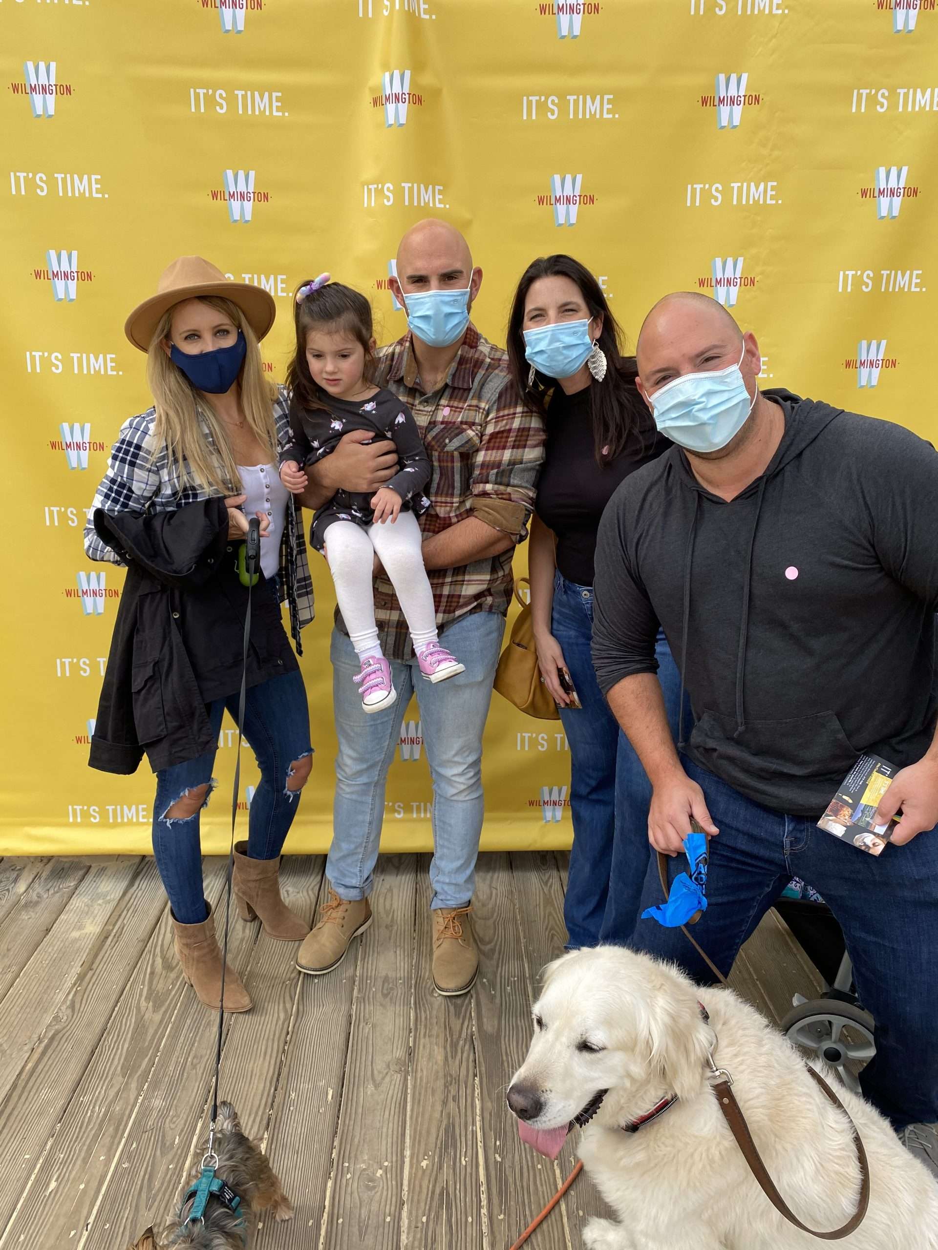 family with dog in front of step and repeat