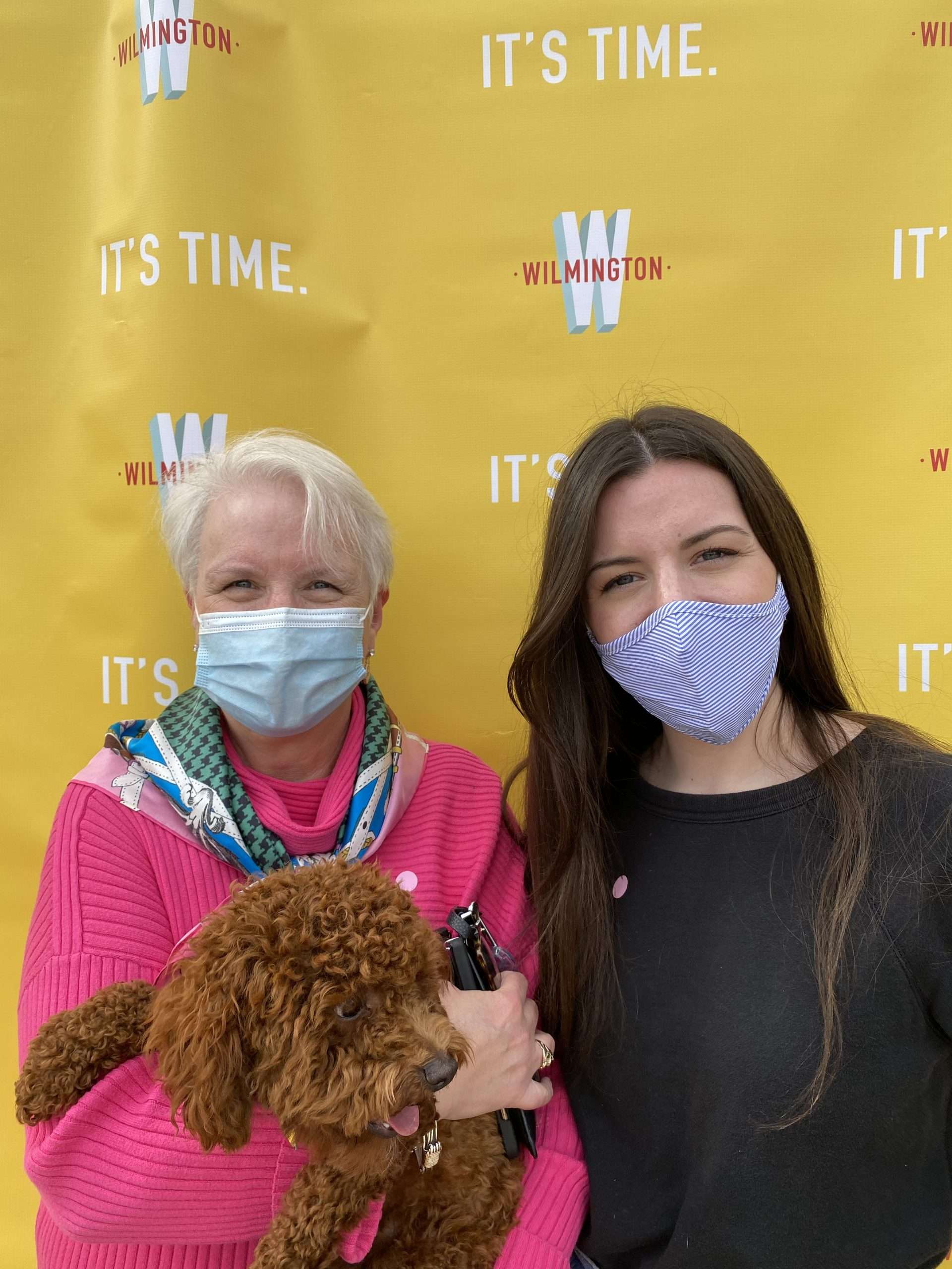 mom and daughter with dog in front of step and repeat